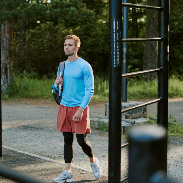 Man in athletic wear walking outdoors with a backpack
