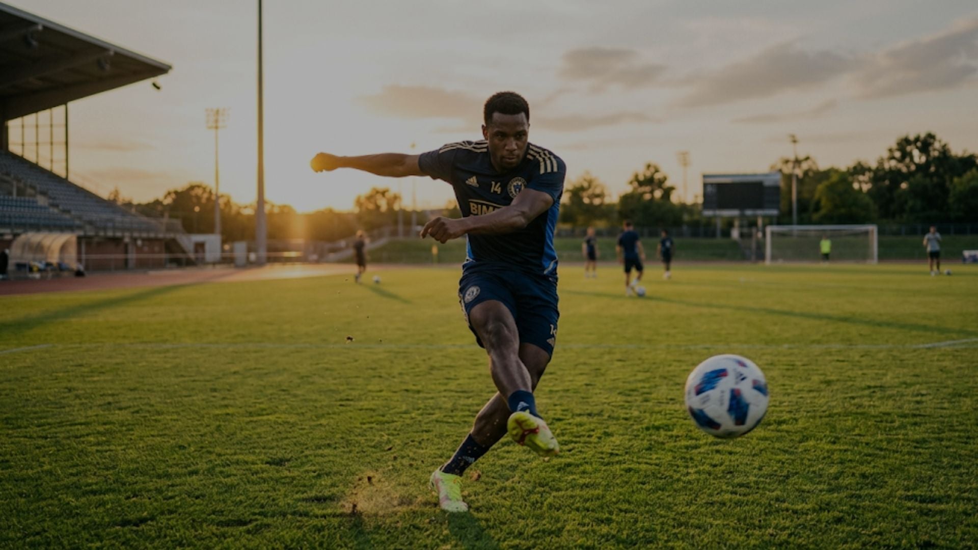 Soccer player in action on a field with sunset in the background
